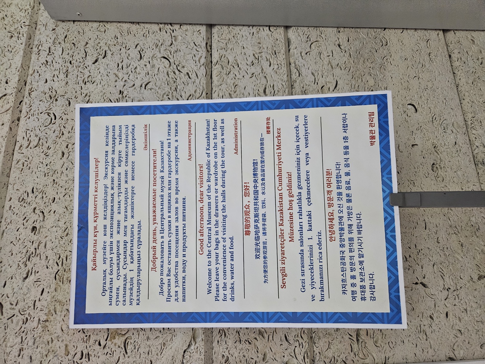 A multilingual visitor sign at Kazakhstan's Central State Museum, with Kazakh and Russian displayed as distinct languages